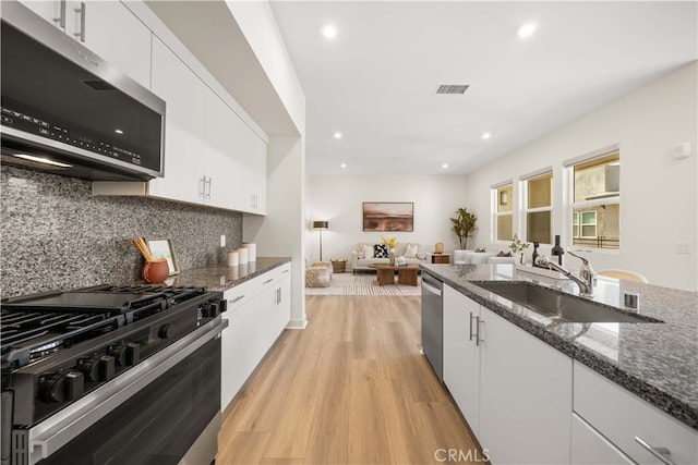 kitchen featuring visible vents, white cabinets, light wood-style flooring, appliances with stainless steel finishes, and a sink