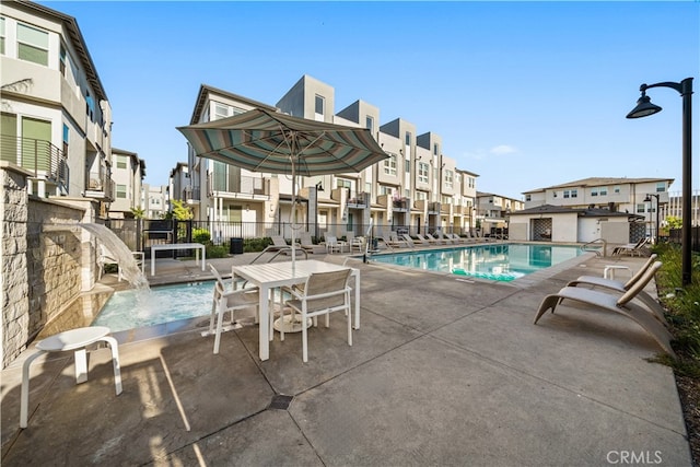 community pool featuring a patio, fence, and a residential view