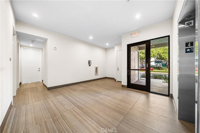 empty room featuring recessed lighting, elevator, french doors, and baseboards