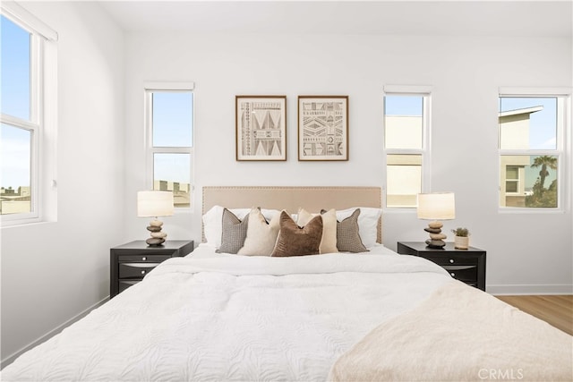 bedroom featuring multiple windows, baseboards, and wood finished floors