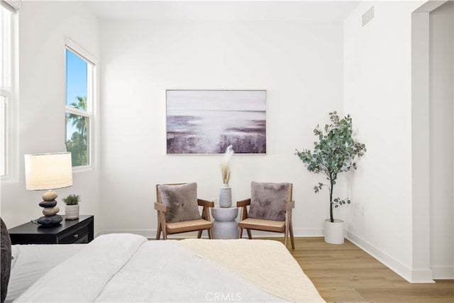 bedroom featuring visible vents, light wood-style flooring, and baseboards