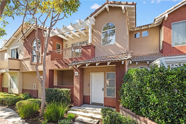 townhome / multi-family property featuring a tile roof and stucco siding