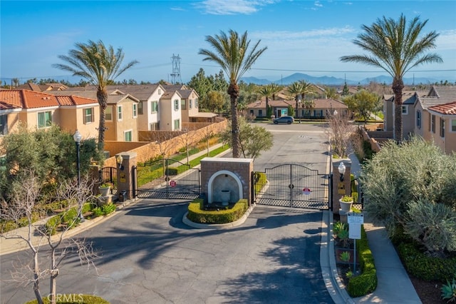 view of street featuring a residential view, a gate, a gated entry, and street lights