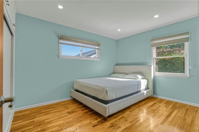 bedroom featuring baseboards, multiple windows, recessed lighting, and light wood-style floors