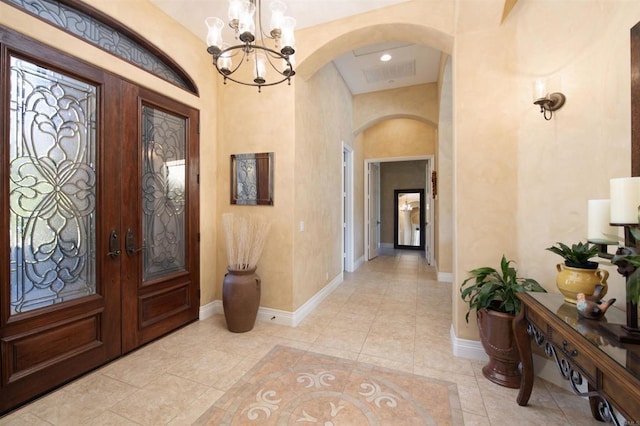 foyer entrance with arched walkways, french doors, visible vents, and baseboards