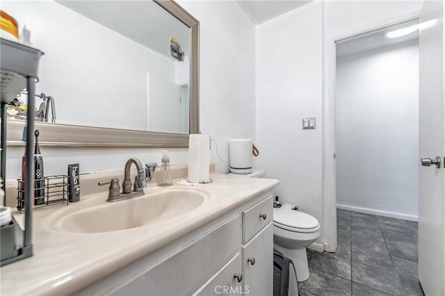 bathroom featuring baseboards, vanity, and toilet