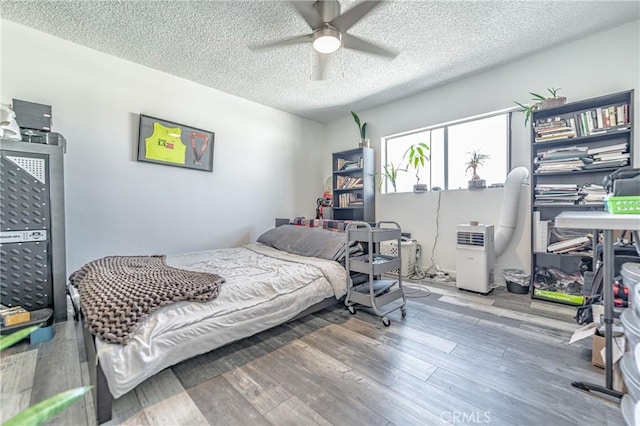 bedroom with a ceiling fan, a textured ceiling, and wood finished floors