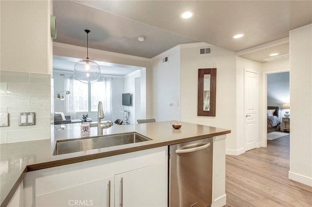 kitchen featuring ornamental molding, white cabinetry, a sink, and dishwasher