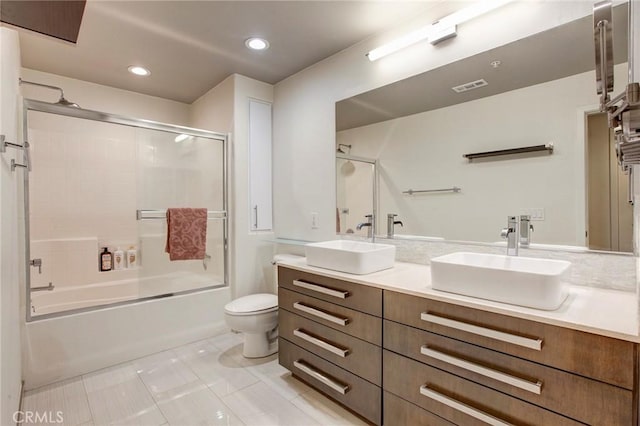 bathroom featuring toilet, double vanity, visible vents, and a sink