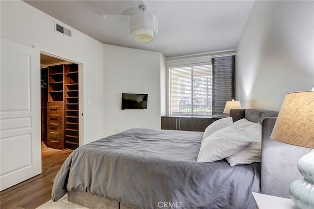 bedroom featuring a closet, a spacious closet, visible vents, and wood finished floors