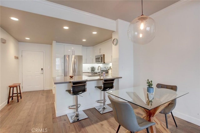 dining room with light wood-style flooring, baseboards, and recessed lighting