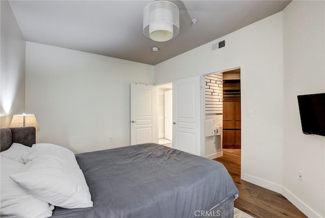 bedroom featuring visible vents, baseboards, and wood finished floors