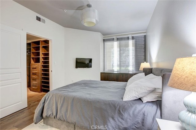 bedroom featuring wood finished floors, a closet, a walk in closet, and visible vents