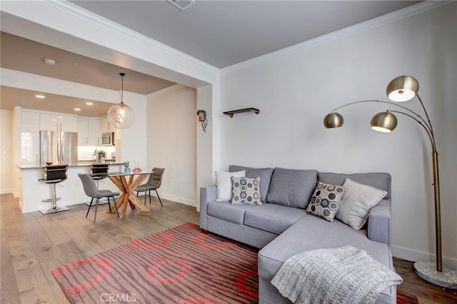 living room with light wood-type flooring, baseboards, ornamental molding, and recessed lighting