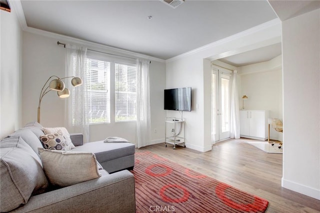 living room with light wood finished floors, baseboards, and ornamental molding