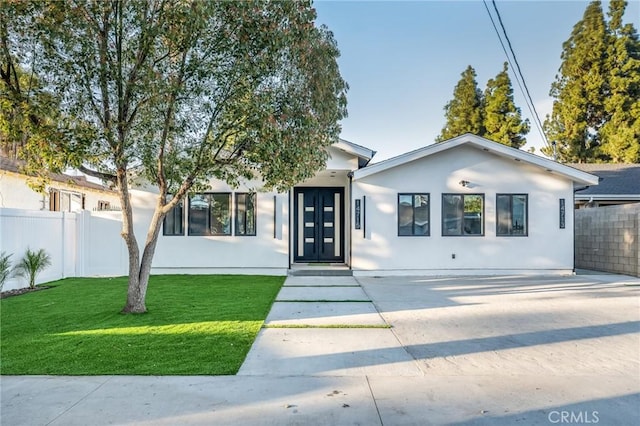 ranch-style home featuring a front yard, fence, and stucco siding