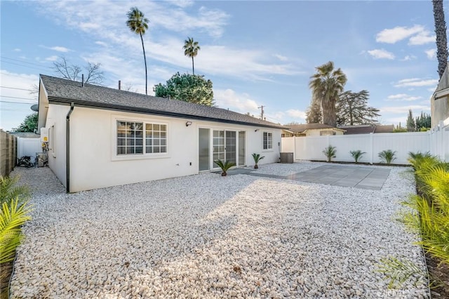 back of house featuring central AC unit, a patio area, a fenced backyard, and stucco siding