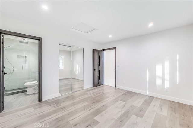 unfurnished bedroom with ensuite bathroom, baseboards, a closet, and light wood finished floors