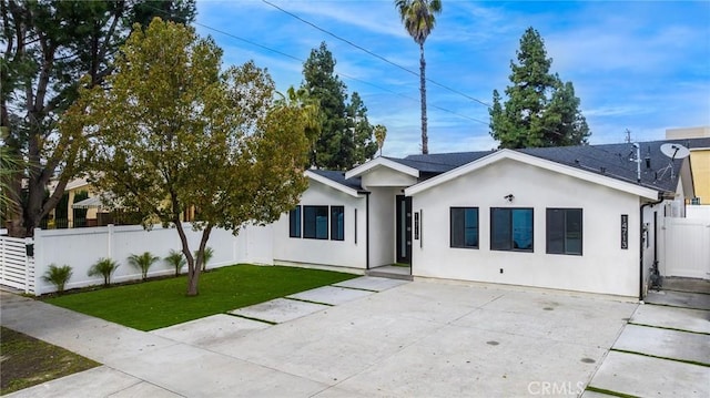 single story home featuring stucco siding, a front lawn, and fence