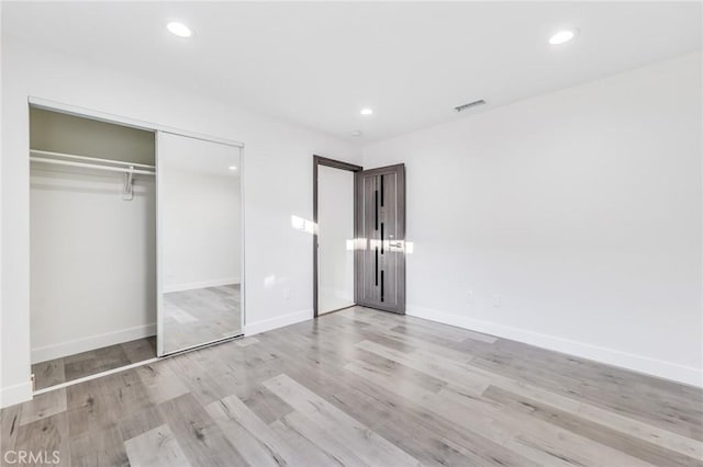 unfurnished bedroom featuring visible vents, baseboards, recessed lighting, wood finished floors, and a closet