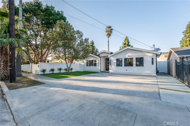 view of front facade featuring stucco siding, driveway, and fence