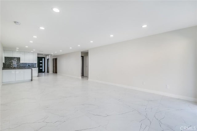 unfurnished living room with recessed lighting, baseboards, and marble finish floor