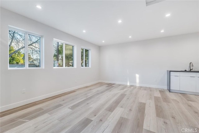 spare room featuring recessed lighting, baseboards, light wood-style floors, and a sink