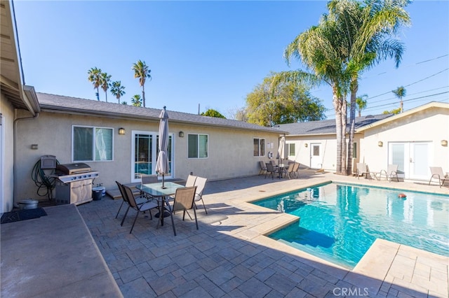 outdoor pool featuring a patio area, a grill, and outdoor dining space