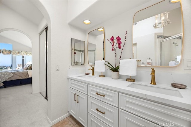 ensuite bathroom with double vanity, a shower stall, a sink, and ensuite bathroom