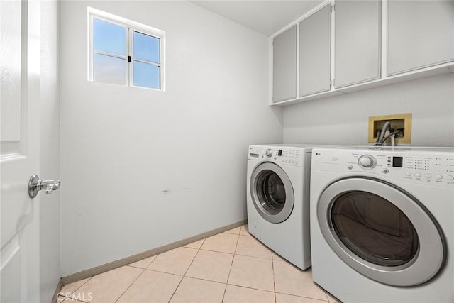 washroom with light tile patterned flooring, washing machine and dryer, cabinet space, and baseboards