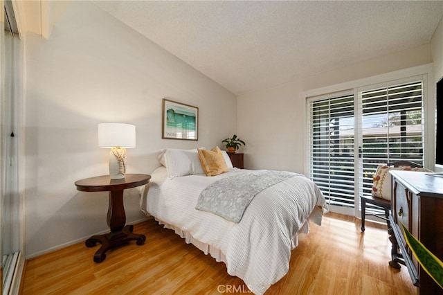 bedroom with vaulted ceiling, light wood finished floors, and baseboards