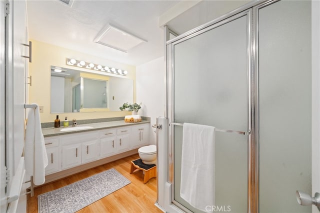 full bathroom featuring toilet, a stall shower, wood finished floors, and vanity