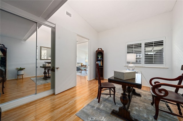 office space featuring vaulted ceiling, light wood finished floors, visible vents, and baseboards