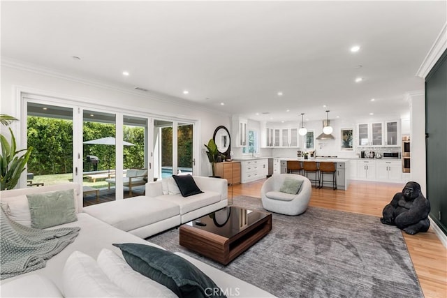 living area with ornamental molding, recessed lighting, and light wood-style floors