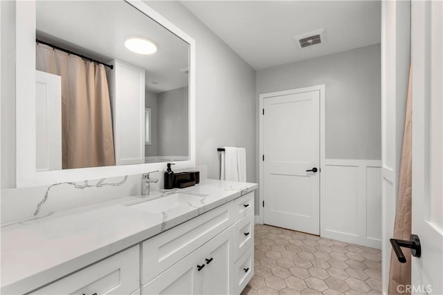 bathroom with a wainscoted wall, tile patterned flooring, vanity, and visible vents