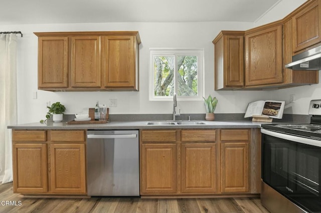 138 S Bryn Mawr St Unit 40, Ventura, CA 93003 - kitchen featuring appliances with stainless steel finishes, under cabinet range hood, brown cabinets, dark countertops, and wood finished floors
