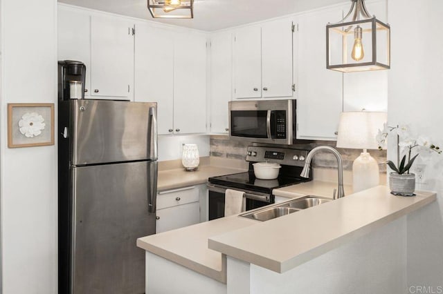 kitchen with decorative backsplash, appliances with stainless steel finishes, a peninsula, light countertops, and white cabinetry