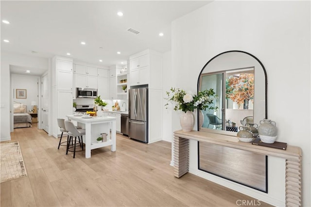 kitchen featuring stainless steel appliances, white cabinetry, visible vents, open shelves, and light wood finished floors