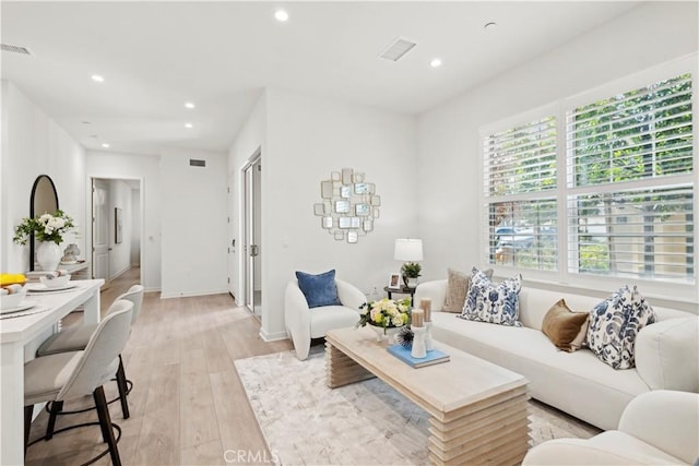 living room with light wood-style flooring, visible vents, baseboards, and recessed lighting