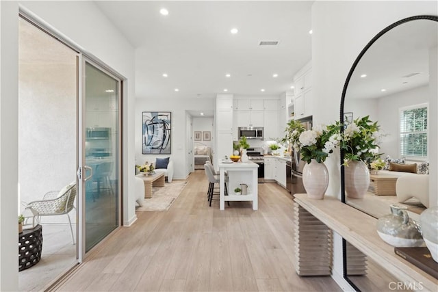 hall featuring light wood-type flooring, visible vents, and recessed lighting