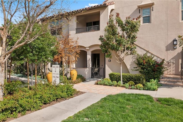 view of front of house with a tiled roof, a gate, a balcony, and stucco siding