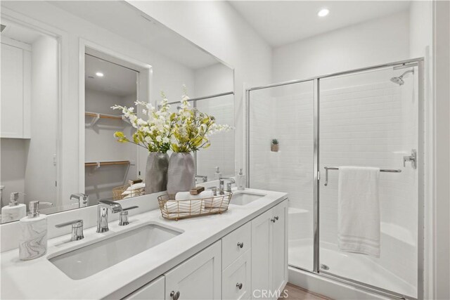 bathroom featuring a sink, a shower stall, and double vanity