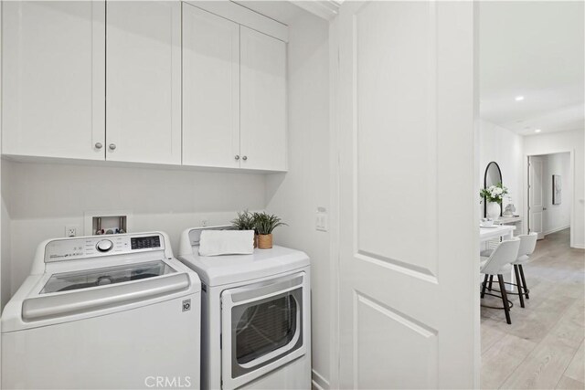 washroom featuring light wood-type flooring, washer and dryer, cabinet space, and recessed lighting