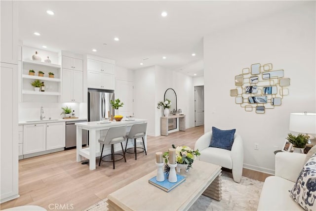 living area with light wood-type flooring, baseboards, and recessed lighting