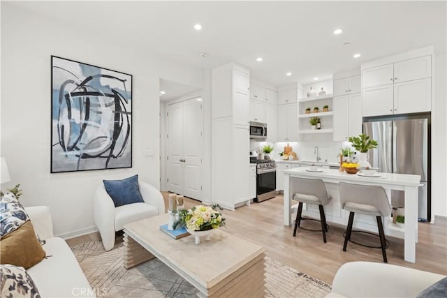 living room with baseboards, light wood-style flooring, and recessed lighting