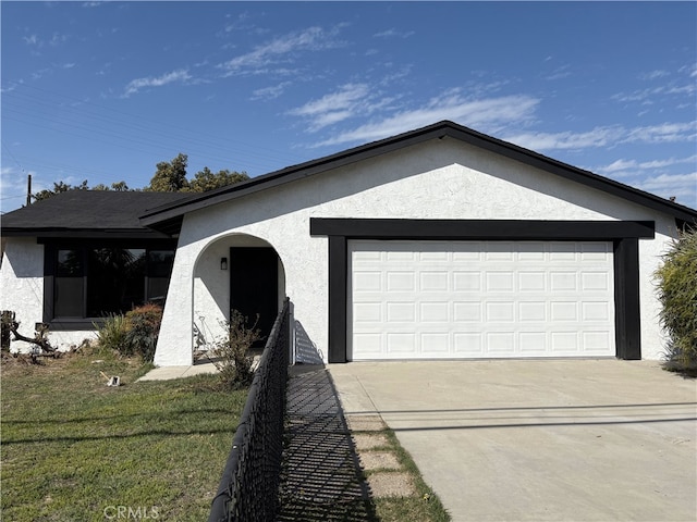 ranch-style house with a garage, driveway, and stucco siding