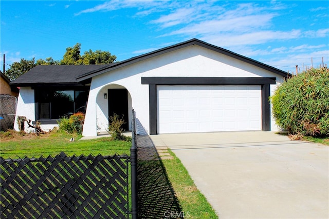 ranch-style house featuring driveway, an attached garage, fence, a front lawn, and stucco siding