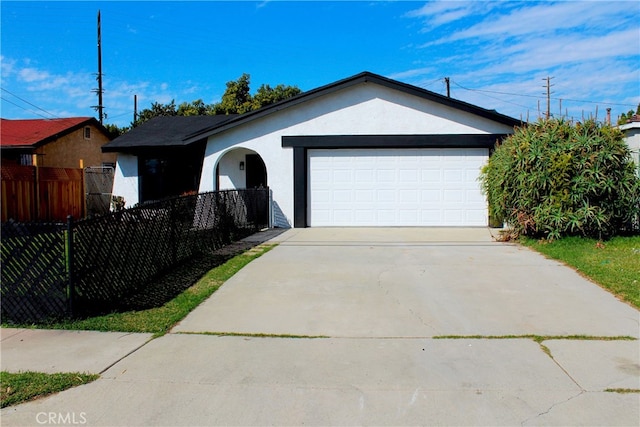 ranch-style house with a garage, driveway, a fenced front yard, and stucco siding