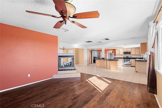 unfurnished living room featuring light wood-style floors, a fireplace, visible vents, and a textured ceiling