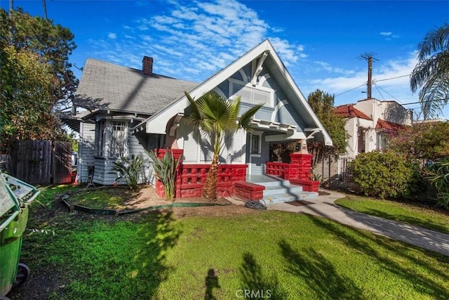 view of front of property with a chimney, a front yard, and fence